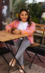 Shani Dhanda sitting at table with drink, outside